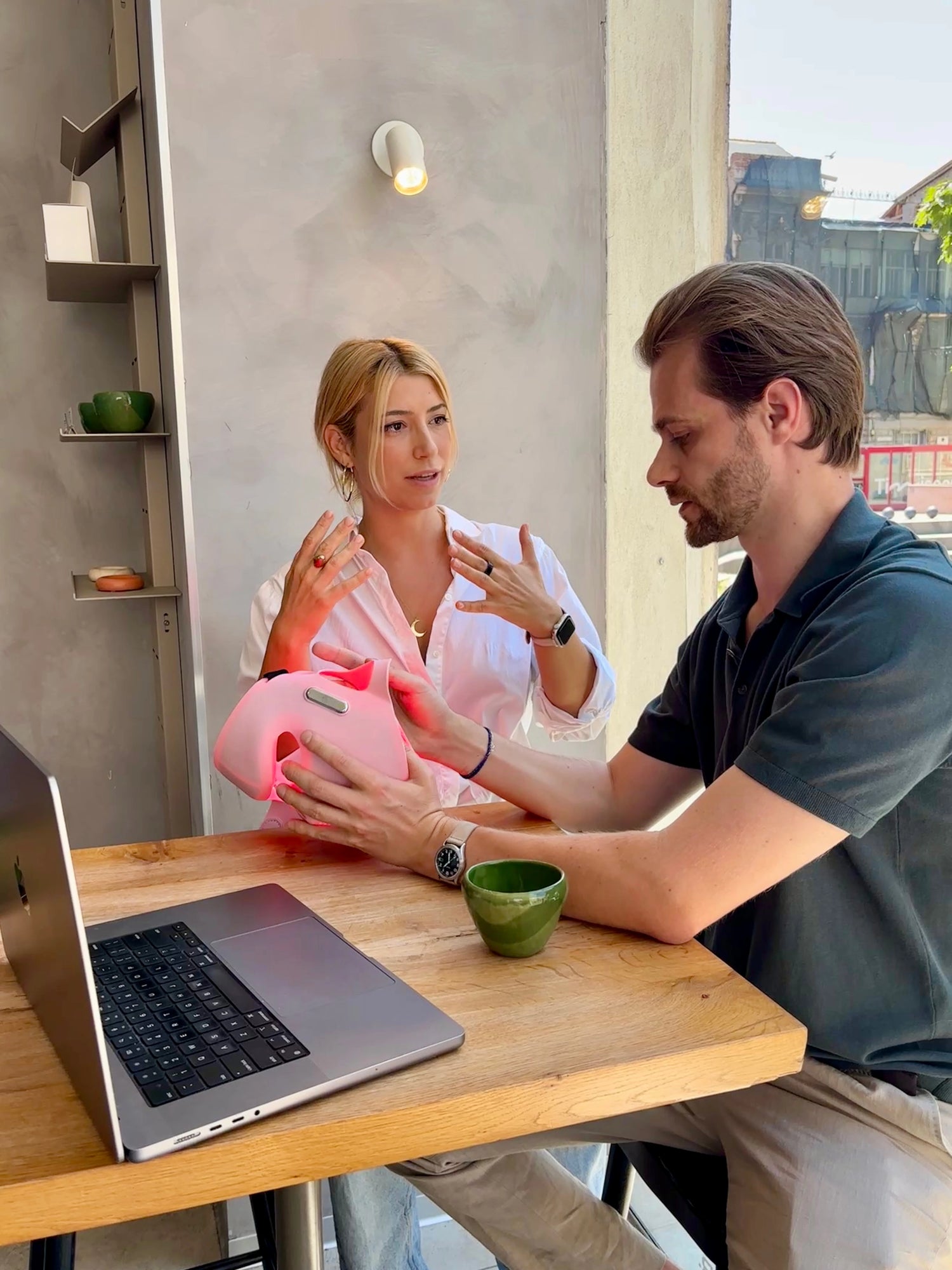 Tina and Nicu, founders of Longera, with the AVA LED face and neck mask while working on a laptop