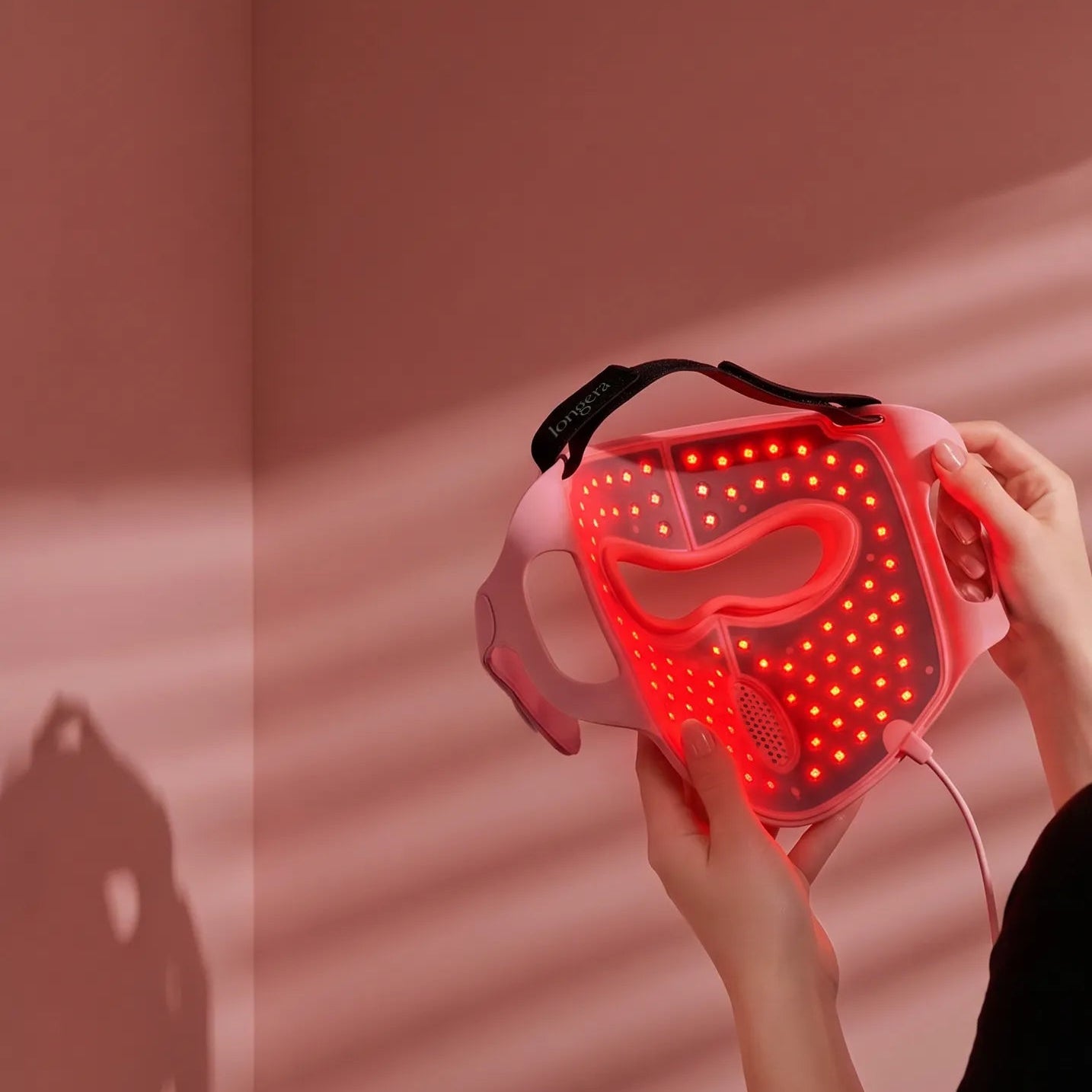 Close-up of a woman holding the Longera AVA LED face and neck mask